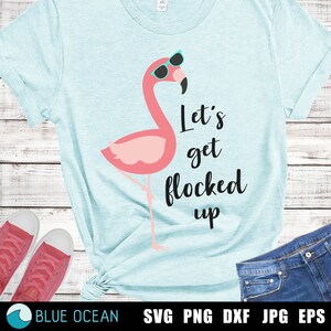 May include: A light blue t-shirt featuring a pink flamingo wearing sunglasses and the text "Let's get flocked up".