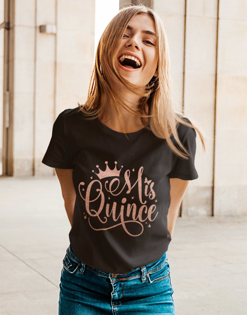 May include: A black t-shirt with a rose gold crown and the text "Es Mi Quince" in a cursive font.