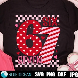 Op de afbeelding: Zwart T-shirt met de cijfers zes en zeven in rood en roze, met een hartjespatroon. Het cijfer zes is bedekt met witte hartjes. Het woord "SIX" is rood en "SEVEN" is roze. Inclusief een dambordpatroon.