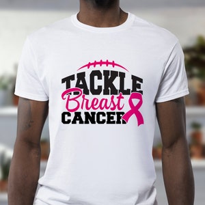 Peut inclure: T-shirt blanc avec un graphisme noir qui dit "Tackle Breast Cancer" avec un ruban rose.