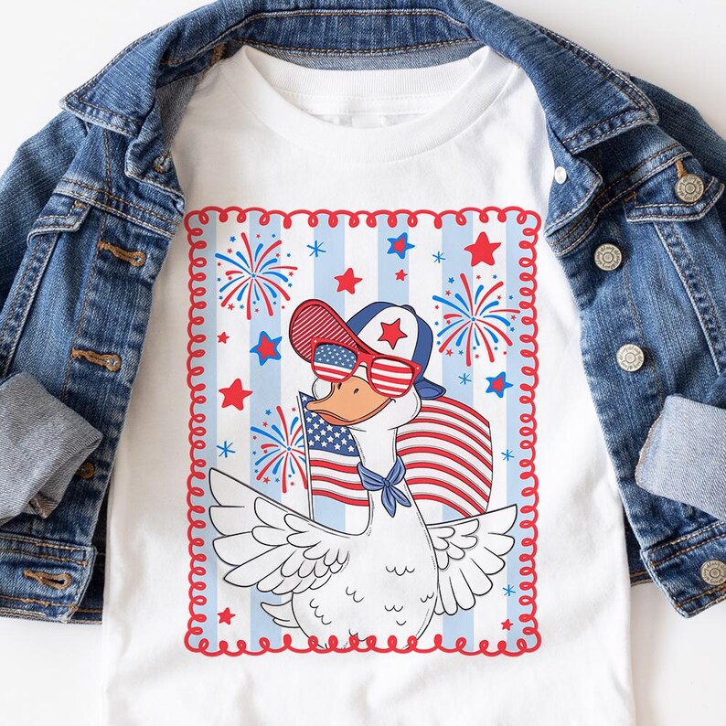 May include: A white t-shirt with a cartoon goose wearing sunglasses and a red, white, and blue hat. The goose is holding an American flag and is surrounded by fireworks and stars. The design is framed by a red, white, and blue border.