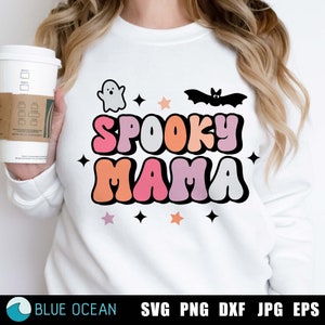May include: A white sweatshirt with the text "Spooky Mama" in colorful retro letters. The text is surrounded by stars and images of a ghost and a bat.