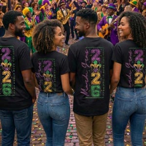 Op de afbeelding: Vier mensen dragen zwarte t-shirts met een kleurrijk "226 Mardi Gras"-ontwerp op de rug, met een fleur-de-lis. Ze staan voor een menigte mensen in feestelijke kleding, die vieren.