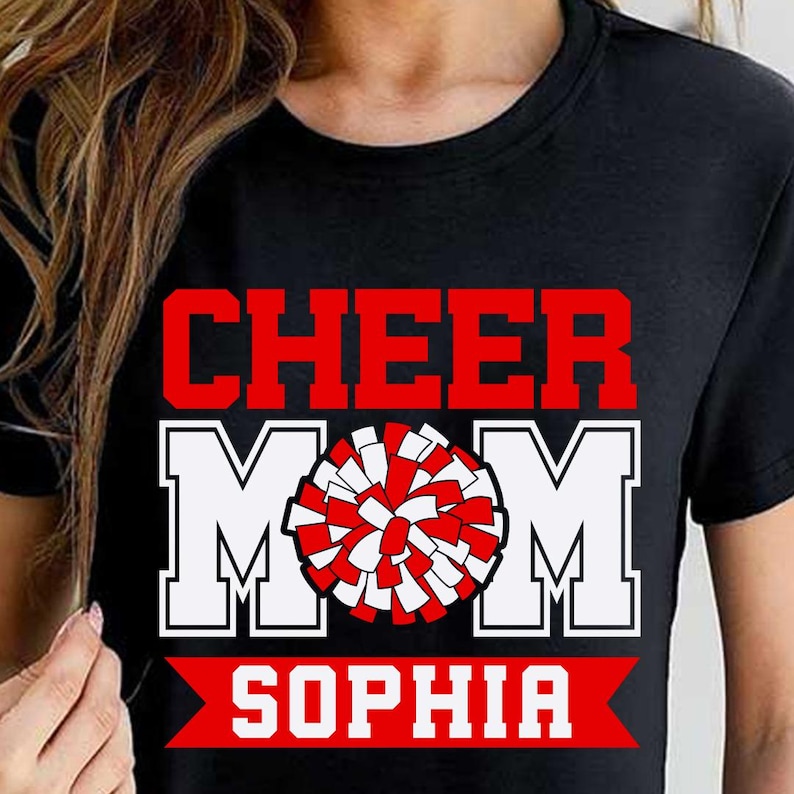 Pode incluir: Camiseta preta com texto branco que diz "Cheer Mom Sophia" e um pompom vermelho e branco.