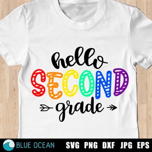 Puede incluir: Una camiseta blanca con el texto "hello second grade" en colores arcoíris. El texto está escrito a mano con una flecha negra que apunta hacia la derecha y la izquierda del texto.