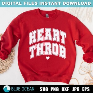 Op de afbeelding: Rood sweatshirt met witte tekst die "HEART THROB" zegt met een klein wit hartje onder de tekst.