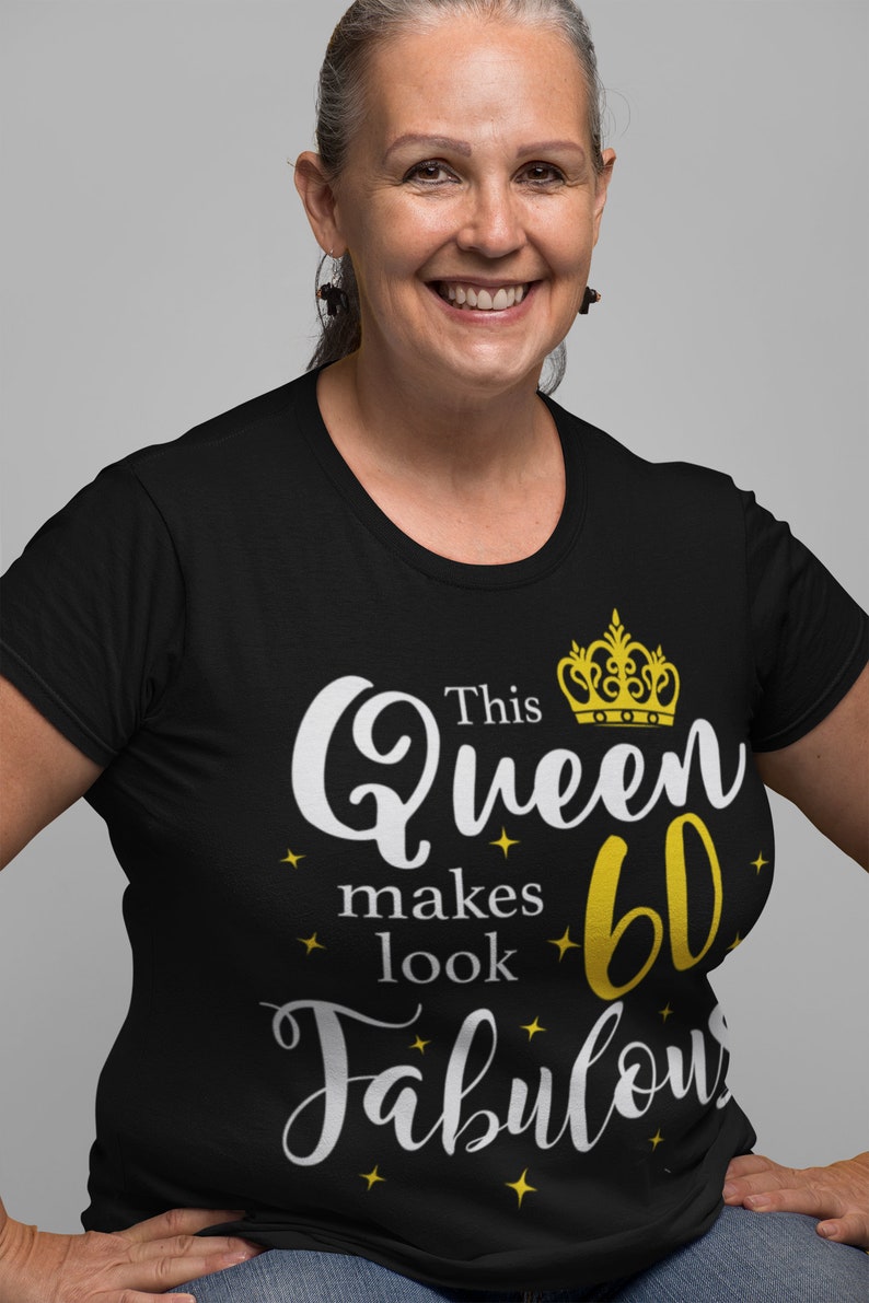 Op de afbeelding: Zwart T-shirt met een witte afbeelding die "This Queen makes 60 look Fabulous" zegt met een gouden kroon boven het woord "Queen".