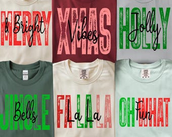 Könnte beinhalten: Sechs T-Shirts in verschiedenen Farben, jedes mit einem Weihnachtsmotto in fetter, verwaschener Schrift. Zu den Sätzen gehören "Merry & Bright", "Xmas Vibes" und "Jolly Holly". Die Shirts werden auf einer flachen Oberfläche präsentiert.