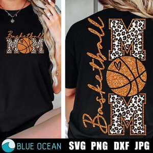 Può includere: T-shirt nero con un design Basketball Mom. Il design presenta le parole "Basketball Mom" in oro glitterato e una grafica di pallone da basket. Le lettere "MOM" hanno un motivo leopardato.