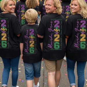 Op de afbeelding: Een groep mensen draagt zwarte t-shirts met een Mardi Gras-ontwerp. Het ontwerp bevat het nummer "226" in paars, goud en groen, samen met de woorden "Mardi Gras" en "Let the Good Times Roll".