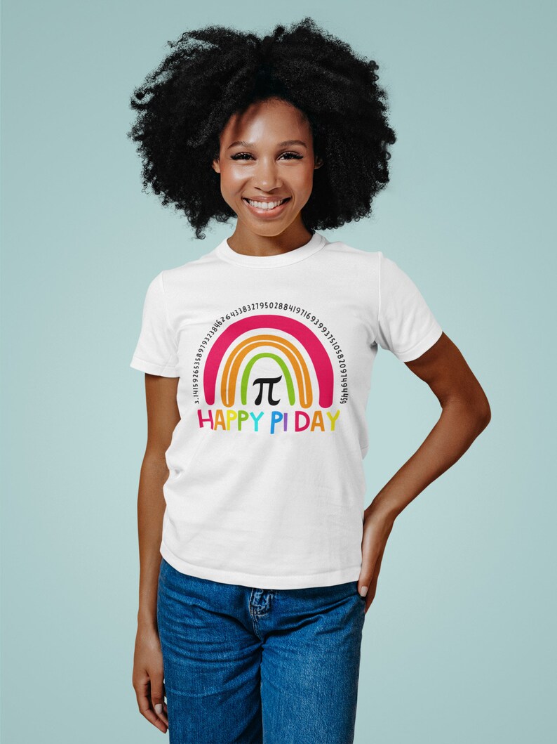 May include: White t-shirt featuring a rainbow design with the text "HAPPY PI DAY". The rainbow includes the mathematical symbol &pi; and a series of numbers. The shirt is made of a soft material.