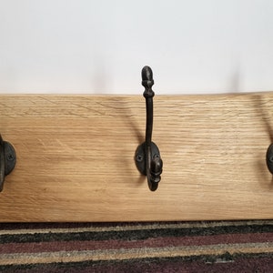 May include: A wooden coat rack with three black metal hooks. The hooks have acorn-shaped finials.