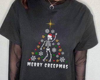 May include: Black t-shirt with a skeleton dressed as a Christmas tree. The text "Merry Creepmas" is printed below the skeleton.