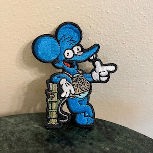 May include: Blue cartoon mouse wearing a camouflage vest and holding a green and brown weapon. The mouse is pointing with its right hand and has a big smile on its face.