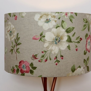 May include: A beige lampshade with a floral pattern featuring white and pink flowers on a linen fabric.