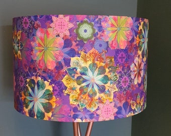 May include: A floor lamp with a purple lampshade featuring a colourful floral pattern. The lampshade has a variety of flowers and intricate designs in shades of pink, yellow, green, and blue.