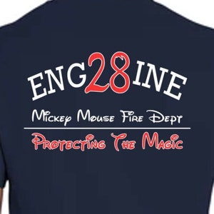 May include: A navy blue t-shirt with the text "ENG28INE" in white with a red "28" in the center. Below the text is "Mickey Mouse Fire Dept" in white and "Protecting the Magic" in red with Mickey Mouse ears.