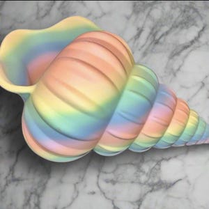 May include: A large, decorative seashell in a spiral shape, painted with pastel rainbow colours. The shell has a wide opening and a textured surface, resting on a marble-patterned background. The colours include pink, yellow, blue, and green.