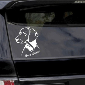 May include: White silhouette of a German Shorthaired Pointer dog's head on a black car window with the text "Grey Ghost" underneath.