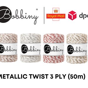 Puede incluir: Cuatro bobinas de hilo metálico trenzado de 3 capas, cada una con una combinación de colores diferente: beige, gris, rojo y dorado. Cada bobina tiene una etiqueta con la marca "Bobbiny" en un óvalo negro. El texto "METALLIC TWIST 3 PLY (50m)" está en la parte inferior.