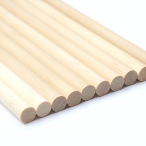 Puede incluir: Un grupo de diez clavijas de madera natural, dispuestas en forma de abanico, con los extremos de las clavijas mirando al espectador. Las clavijas son todas del mismo tama&ntilde;o y de color marr&oacute;n claro.