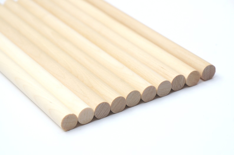 Puede incluir: Un grupo de diez clavijas de madera natural, dispuestas en forma de abanico, con los extremos de las clavijas mirando al espectador. Las clavijas son todas del mismo tama&ntilde;o y de color marr&oacute;n claro.