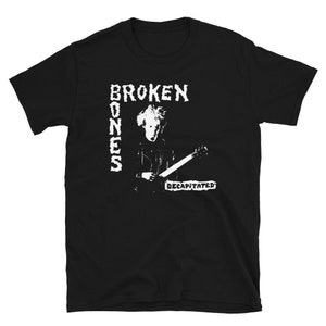 May include: Black t-shirt with a white graphic of a person playing a guitar. The text "BROKEN BONES DECAPITATED" is printed on the shirt.