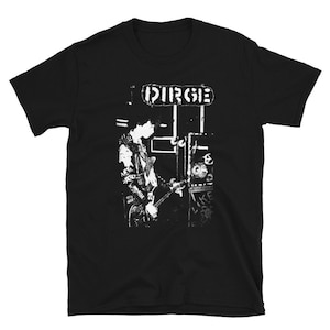 May include: Black t-shirt featuring a white graphic of a person playing a guitar in front of a sign that reads "DIRGE".
