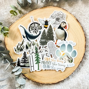 May include: A set of colourful stickers with nature-themed designs, including a compass, a whale, a bee, a tree, a puffin, a paw print, and text that reads "Save the bees, protect the trees, clean the seas".