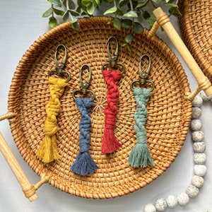 May include: Four colorful braided keychains with gold key rings. The keychains are yellow, red, blue, and green.