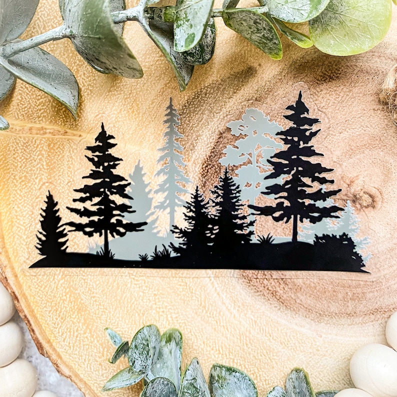 May include: Silhouette of a forest with black trees against a light blue background. The trees are arranged in a row, with the tallest tree in the centre. The image is ideal for adding a touch of nature to any project.
