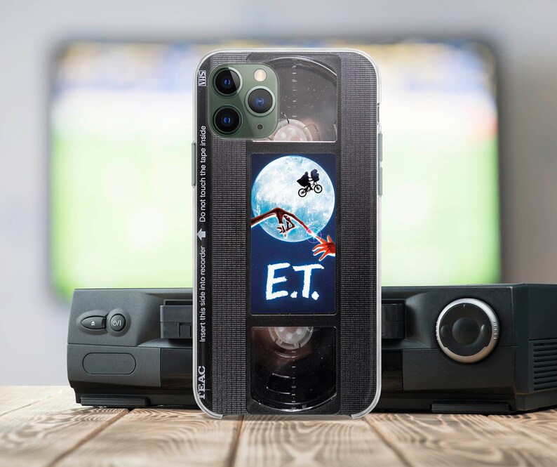 May include: A black and silver iPhone case with a vintage VHS tape design. The case features a scene from the movie E.T. with the text "E.T." printed on the case.