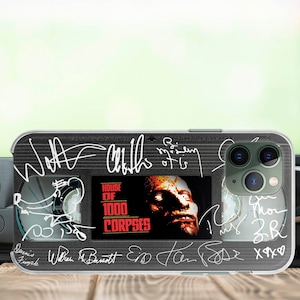 May include: A clear phone case with a black and white image of a VHS tape. The tape has the title "House of 1000 Corpses" and several signatures. The case has a cutout for the phone's camera.