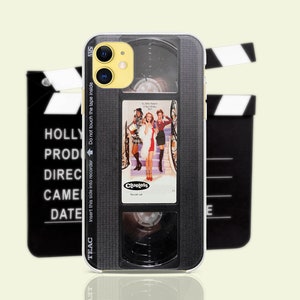 May include: A black and silver iPhone case with a vintage VHS tape design. The case features a movie poster for the film "Clueless" with the text "Insert this side into recorder Do not touch the tape inside" and "TEAC" printed on the side.