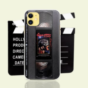 May include: A black and silver iPhone case with a vintage VHS tape design. The case features a werewolf from the movie "An American Werewolf in London". The text "Insert this side into recorder Do not touch the tape inside" is printed on the side of the case.