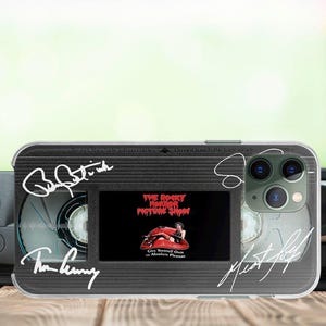 May include: A black and silver iPhone case with a cassette tape design. The case features a signature from the movie "The Rocky Horror Picture Show" and the text "Give Yourself Over to Absolute Pleasure".