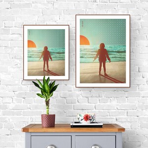 May include: Two framed prints depicting a person standing on a beach with the sun setting in the background. The prints are of different sizes and are hung on a white brick wall.
