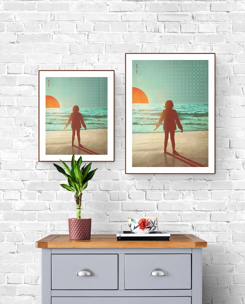 May include: Two framed prints depicting a person standing on a beach with the sun setting in the background. The prints are of different sizes and are hung on a white brick wall.