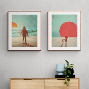 May include: Two framed prints with a beach theme. The first print shows a person standing on a beach with a large red sun setting in the distance. The second print shows two people walking on a beach with a large red sun in the sky.