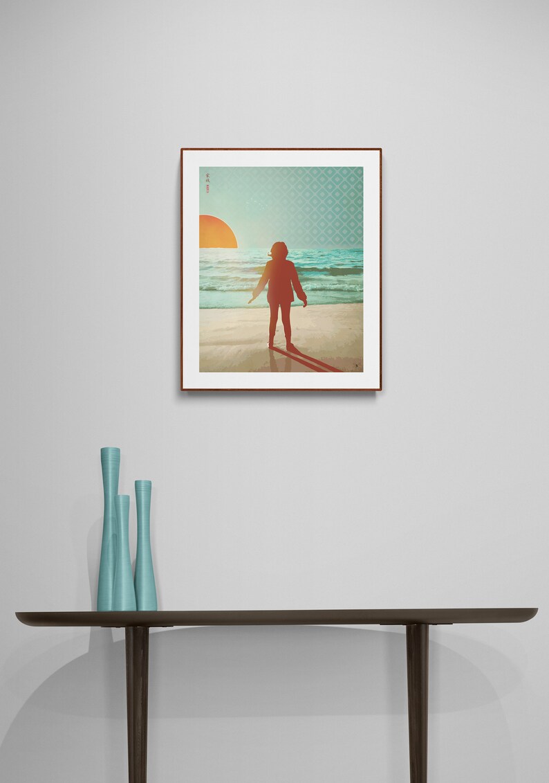 May include: A framed print depicting a silhouette of a person standing on a beach with the sun setting in the background. The print has a blue and green geometric pattern border.