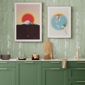 May include: A green kitchen with a marble countertop and green cabinets. There are two framed prints on the wall, one with a mountain and a red sun, and the other with a fish in a circle. There are cooking supplies on the counter, including a pot, a pan, and bottles of oil.