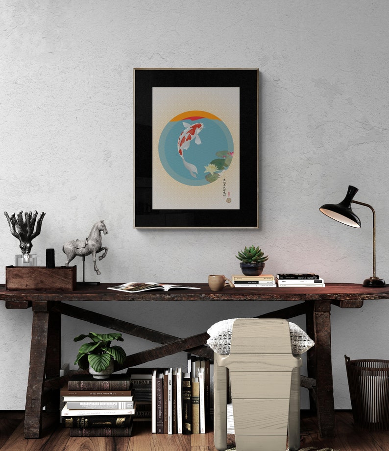 May include: A framed print of a koi fish swimming in a circle with water lilies and a Japanese character. The print is hanging on a white wall above a wooden desk with a lamp, books, and a chair.