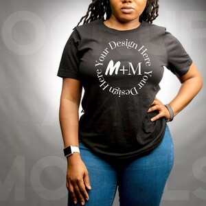 May include: A black t-shirt with a white circle design that says "Design Your Here M+M Design Your Here".