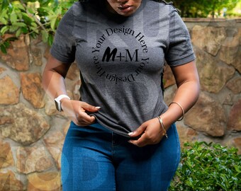 May include: A gray t-shirt with a black circle design that says "Design Your Design Here" with the letters M+M in the center.