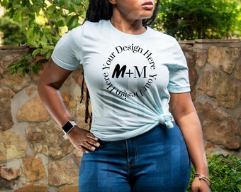 May include: A light blue t-shirt with a circle design that says "Design Your Here M+M Your Design Here".