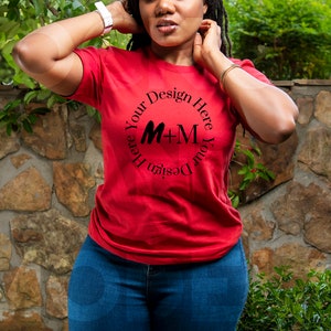 May include: A red t-shirt with a black circle design that says "Design Your Here Your Design Here" with the letters M+M in the center.
