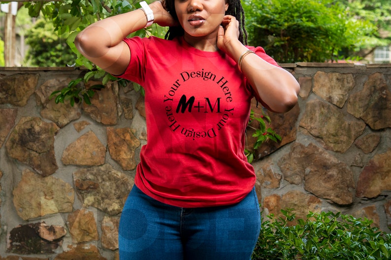May include: A red t-shirt with a black circle design that says "Design Your Here Your Design Here" with the letters M+M in the center.