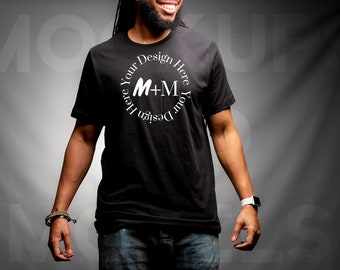 May include: A black t-shirt with a white circle design that says "Your Design Here M+M Your Design Here".