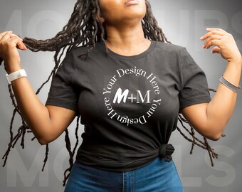 May include: A black t-shirt with a white circle design that says "Design Your Here Your Design Here" and has the letters "M+M" in the center.