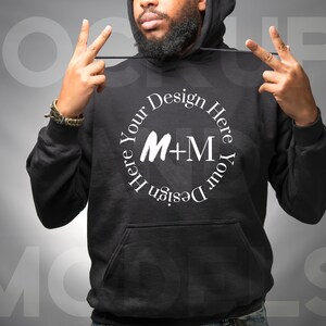 May include: A black hooded sweatshirt with a white circle design featuring the text "Design Your Here Your Design Here" and the letters "M+M".